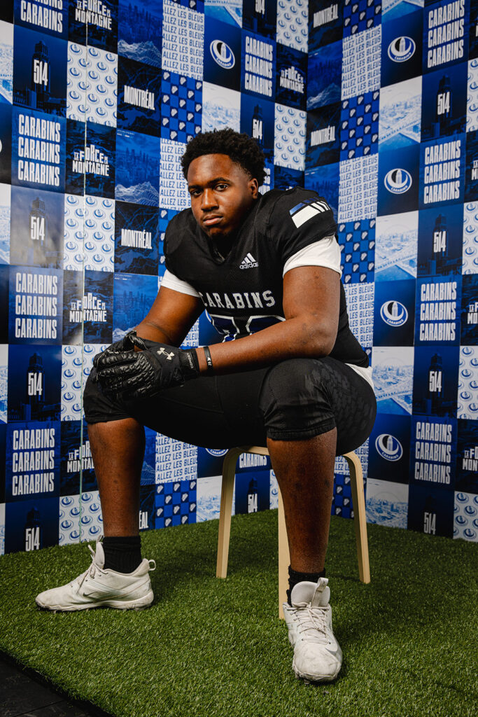 Athlète de football des Carabins devant un mur média aux couleurs de l’équipe.